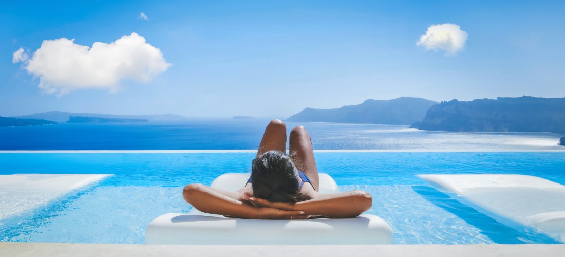 eine Frau in den Ferien auf Santorini entspannen in einem Swimmingpool mit Blick auf das Caldera-Meer 
