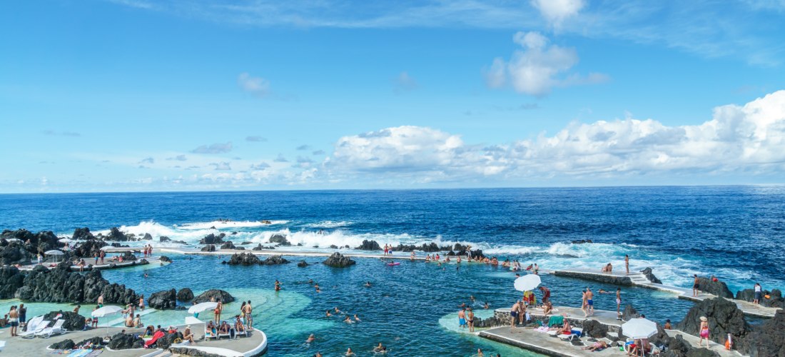 Porto Moniz Madeira – Natürliche Lavapools am Atlantik Natürliche Lavapools in Porto Moniz auf Madeira mit Badegästen und Blick auf den Atlantik unter blauem Himmel