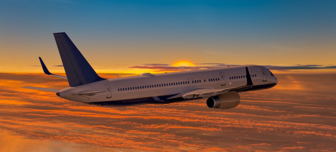 Passagierflugzeug fliegt in den Sonnenuntergang über orange gefärbten Wolken