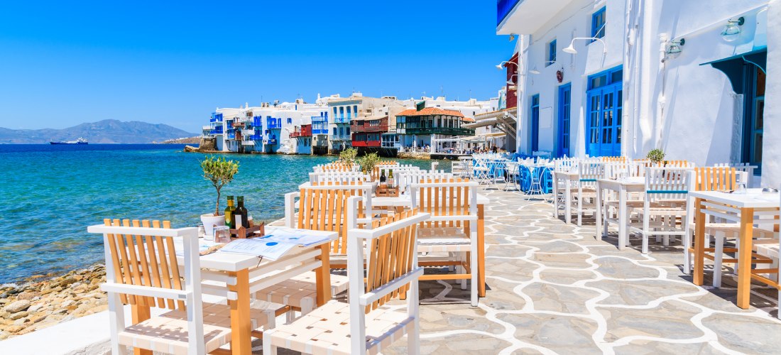 Strandrestaurant mit weißen Stühlen und Tischen direkt am Wasser im Viertel Little Venice auf Mykonos, Griechenland