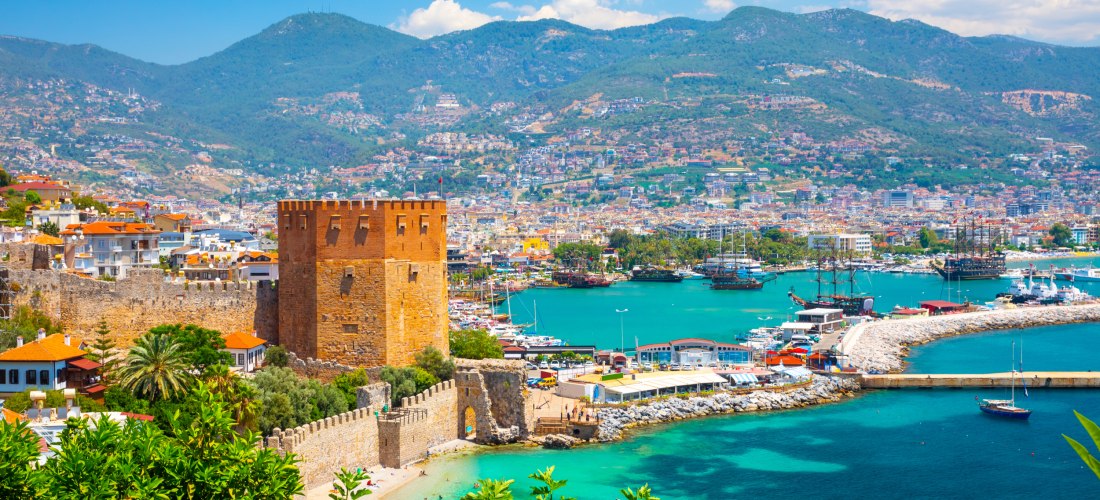 Blick auf den Roten Turm und den Hafen von Alanya mit türkisblauem Wasser und malerischer Altstadt