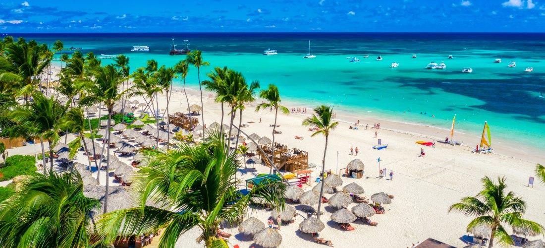 Weißer Sandstrand mit Palmen, türkisblauem Meer und Sonnenschirmen in Punta Cana, Dominikanische Republik