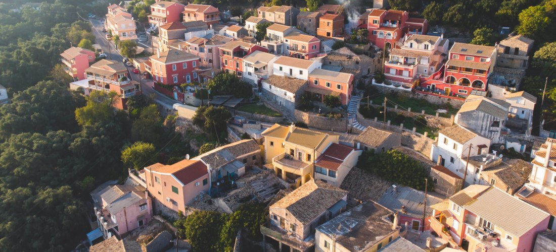 Wunderschöne Luftdrohnenansicht des Dorfes Lakones, traditionelles griechisches Dorf in der Nähe von Paleokastritsa, Insel Korfu, Kerkyra, Ionische Meeresinseln, Griechenland, an einem sonnigen Sommertag mit blauem Himmel und Bergen