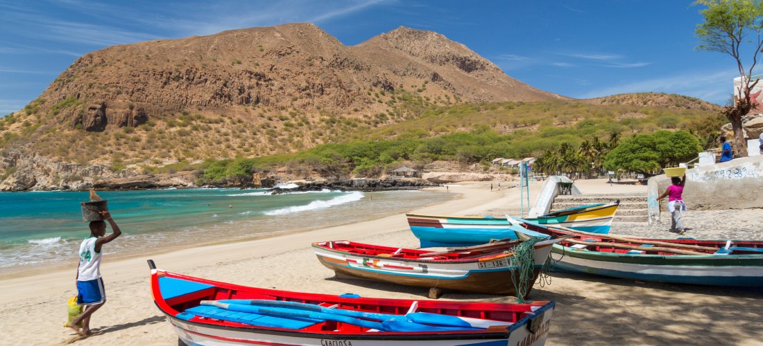 Strand von Tarrafal auf der Insel Santiago, Kapverden – bunte Fischerboote im Sand und felsige Berge im Hintergrund
