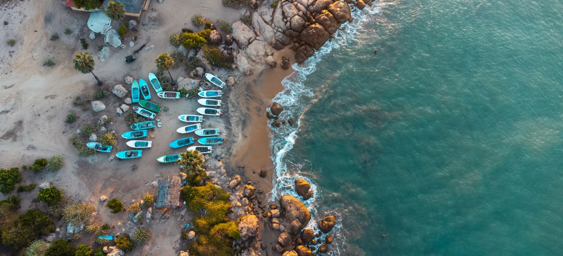 Luftaufnahme von Fischerbooten und Felsen an der Küste von Arugam Bay in Sri Lanka mit türkisblauem Meer