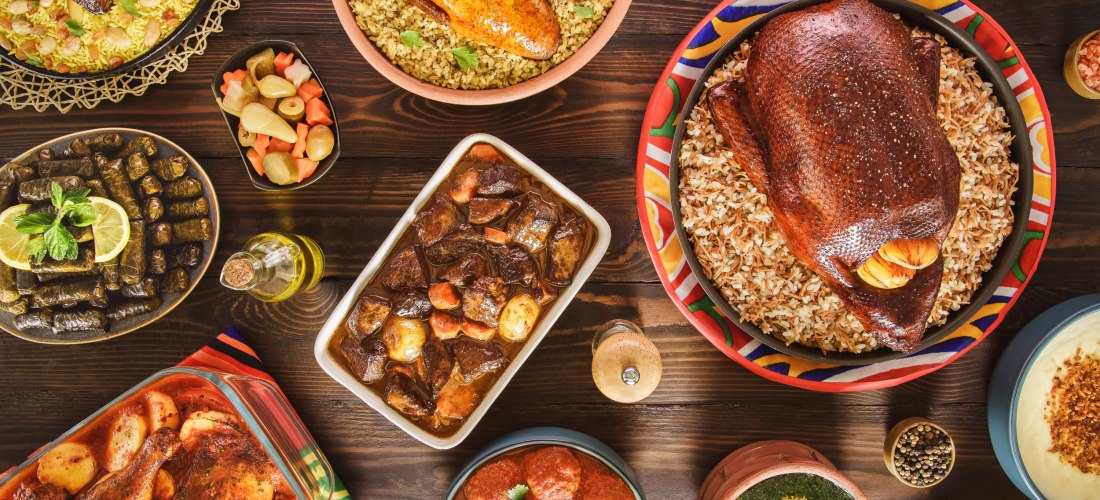 Ein festliches Buffet mit orientalischen Speisen: gefüllte Weinblätter, gebackenes Hähnchen, Fleischragout, gefüllte Tauben, ganze Ente auf Reis, eingelegtes Gemüse, rote Soße mit Fleischbällchen, Molokhia, Kartoffelhähnchen aus dem Ofen und verschiedene 