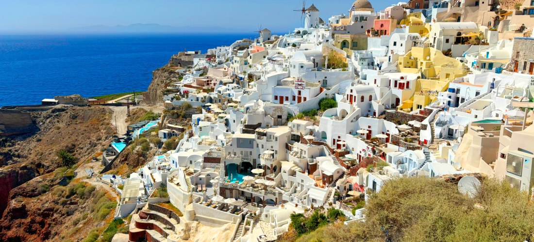 Panorama von Oia auf Santorini mit weißen Kykladenhäusern, Windmühle und Blick auf die Ägäis