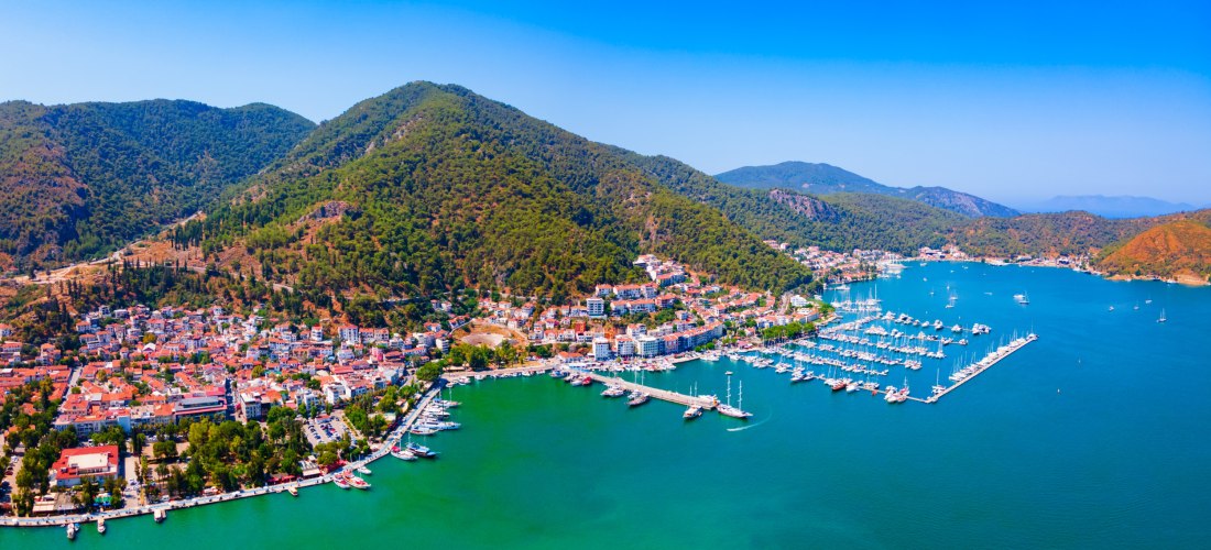 Panoramablick auf die Küstenstadt Fethiye mit Hafen, Booten und grünen Hügeln am türkisblauen Meer