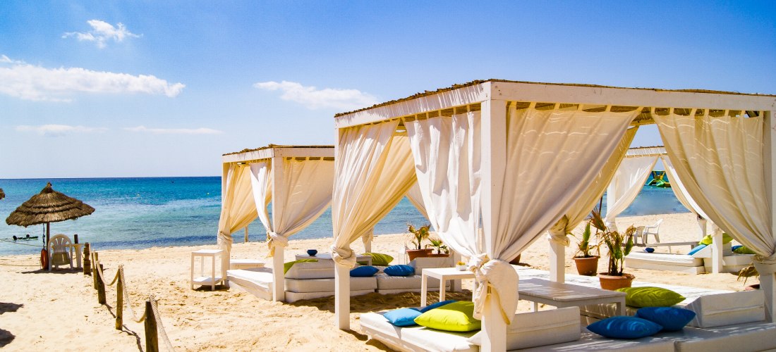 Ein Blick an einem sonnigen Tag am Strand von Hammamet, Tunesien. Mehrere Balibetten ( Liegen mit Überdachung ] Sonne scheint, blauer Himmel, romatische Stimmung