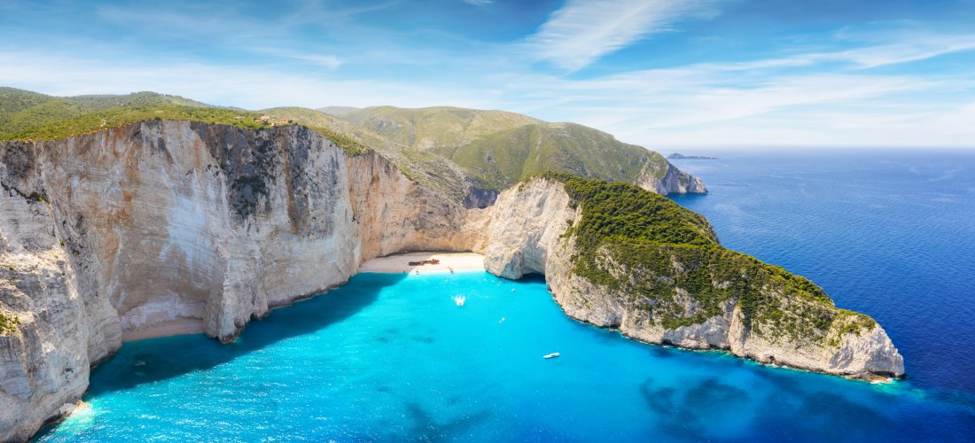 ein kleiner Strand neben einem riesigen Berg und Booten