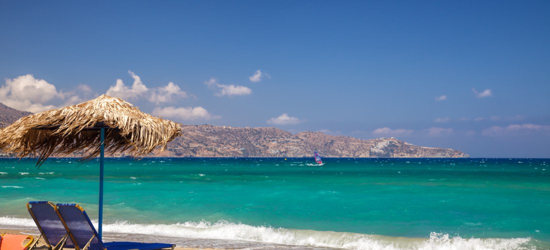 Strand mit Sonnenliegen und Blick auf die Berge