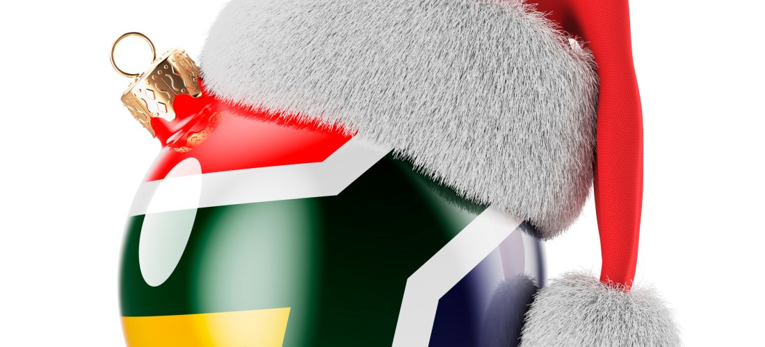 Glänzende Weihnachtskugel mit dem Design der südafrikanischen Flagge, verziert mit einer roten Weihnachtsmütze mit weißem Pelzbesatz.