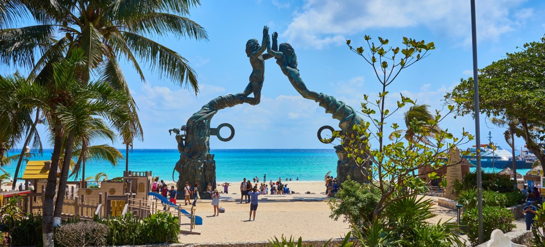  Ein beeindruckendes Monument am Strand mit Blick auf das türkisfarbene Meer, umgeben von Palmen und einem Spielplatz.
