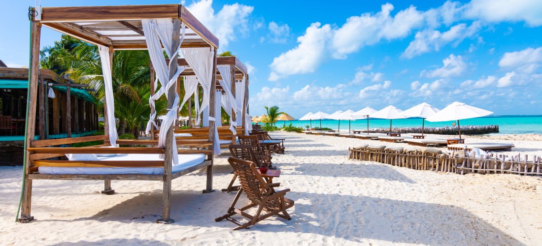 Weiße Sandstrände mit Bali-Betten, Liegestühlen und Sonnenschirmen auf Isla Mujeres in Mexiko – Karibikinsel für Urlaub 2025/2026