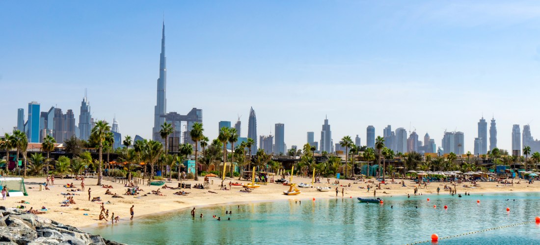 Strand in Dubai mit Menschen und Wolkenkratzern im Hintergrund