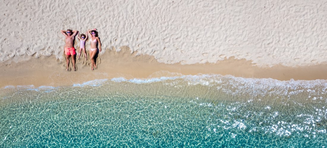glückliche Familie entspannt am Strand mit smaragdgrünem Meer, Kykladen, Griechenland