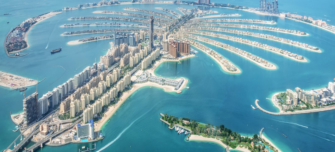 Dubai - The Palm Luftaufnahme der Palm Jumeirah in Dubai, bei der die einzelnen 'Palmwedel' klar zu erkennen sind. Entlang des zentralen 'Stamms' reihen sich Wohnhäuser und Hotels. Auf dem äußeren Ring ist das ikonische Atlantis The Palm Hotel sichtbar. Das türkisfarbene