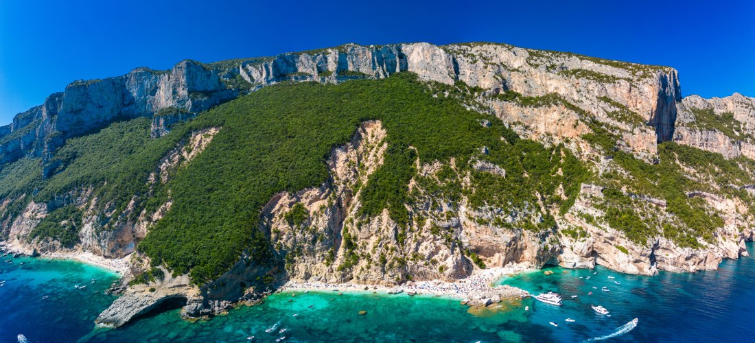 Luftaufnahme der Cala Mariolu auf Sardinien mit Booten im türkisfarbenen Meer, steilen Klippen und weißen Stränden – Highlight an der Ostküste Sardiniens