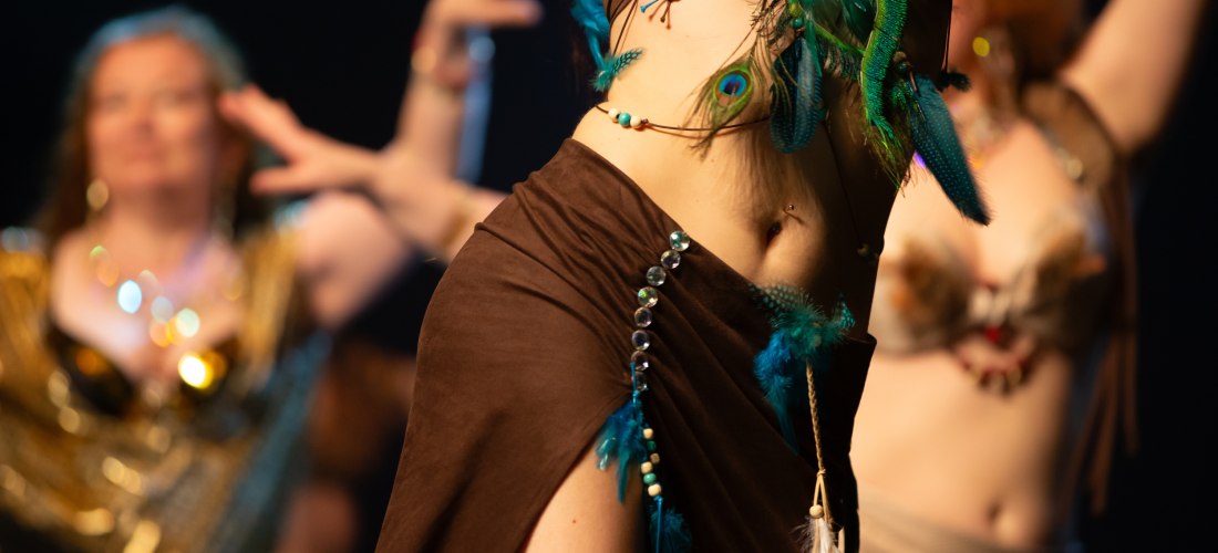 Frauen tanzen orientalischen Bauchtanz. Im Vordergrund 1 Frau , im Hintergrund weitere Frauen unscharf zu sehen, beim tanzen 