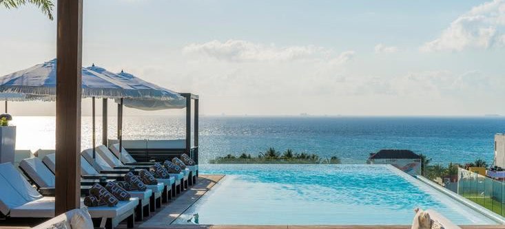 Pool mit Liegen, Sonnenschirmen Blick auf das Meer , im Vordergrund Sofalandschaft