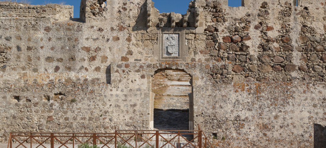 Eingangstor der Johanniterfestung Antimachia auf Kos mit massiven Steinmauern und einem Wappenrelief.