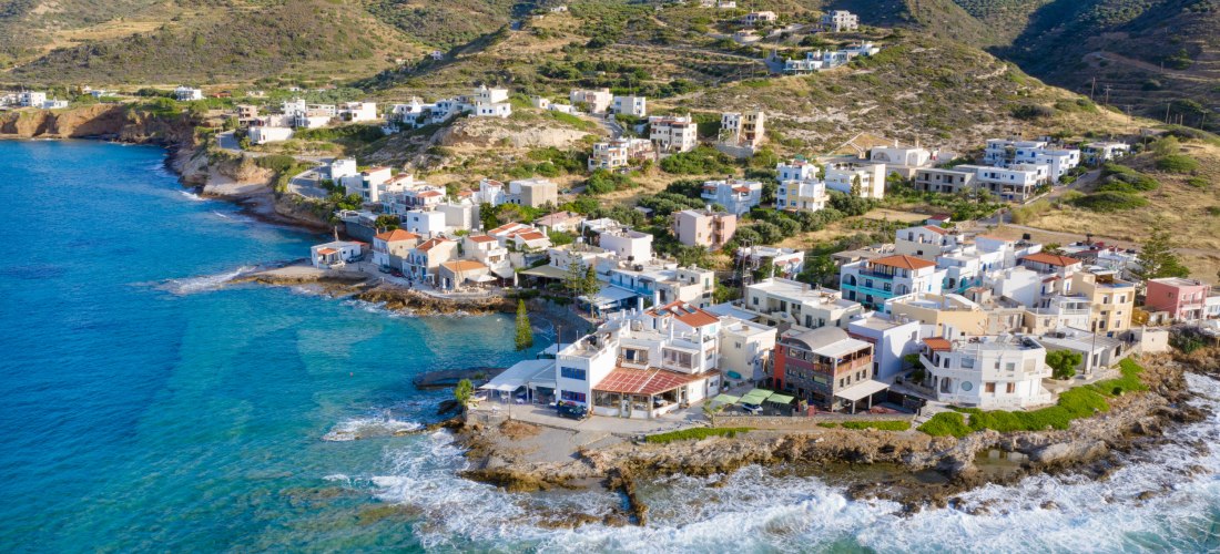Malerischer Küstenort auf Kreta mit Häusern am Hang und Blick auf das Meer