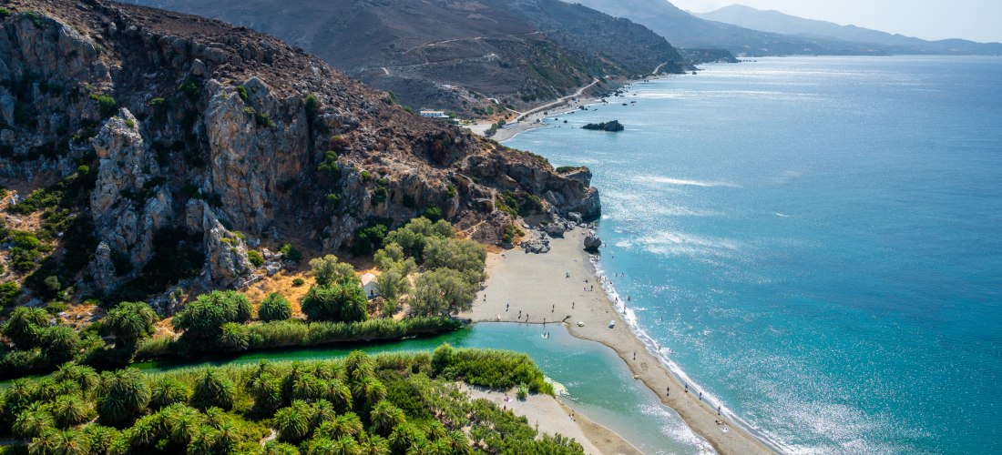 Palmenstrand mit Bergen und Meer im Hintergrund