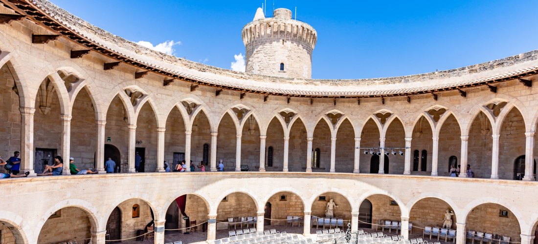 Innenhof des runden gotischen Castell de Bellver in Palma de Mallorca mit Arkaden und Turm bei blauem Himmel