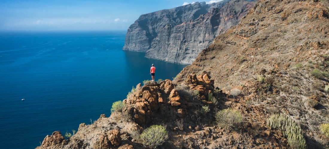 Wanderer blickt auf die beeindruckenden Steilklippen von Los Gigantes auf Teneriffa mit Blick auf den Atlantik