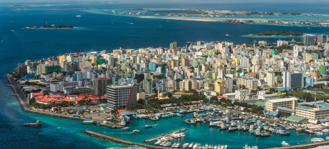 Luftaufnahme von Malé, Malediven – dicht bebaute Inselhauptstadt mit Hafen, Booten und türkisblauer Lagune
