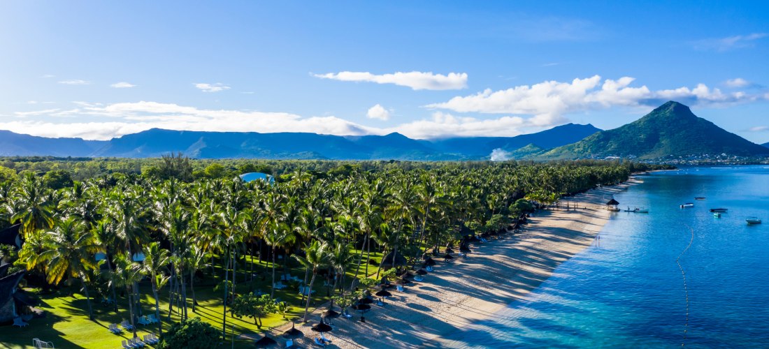 Luftaufnahme des Strandes von Flic en Flac auf Mauritius mit Palmen, türkisfarbenem Wasser und Blick auf den Berg Le Morne