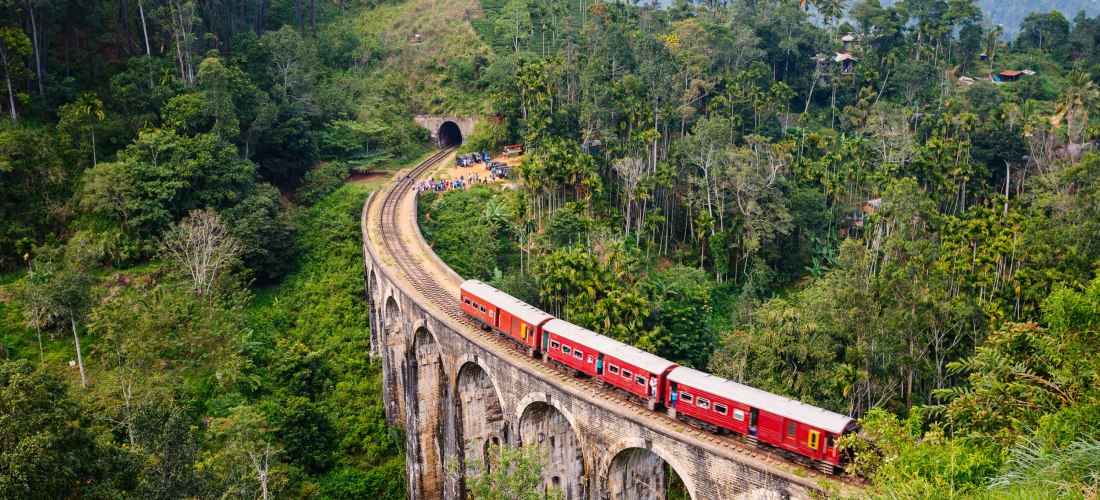 Legendärer Zug auf der Nine Arches Bridge bei Ella in Sri Lanka, umgeben von dichtem Dschungel und Bergen