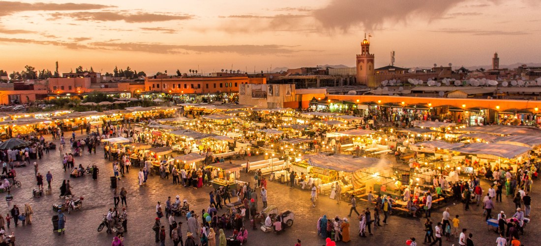 Menschenmengen und leuchtende Marktstände auf dem Djemaa el Fna Platz in Marrakesch, Marokko, bei Sonnenuntergang – lebendige Medina mit orientalischem Flair.