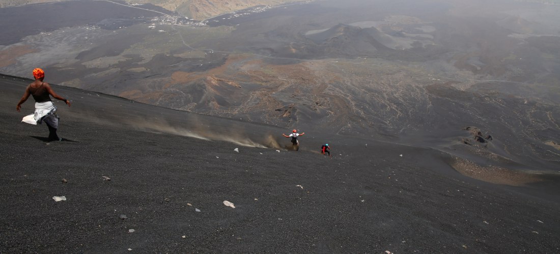 Wanderer am Vulkan Pico do Fogo auf den Kapverden – Abstieg durch schwarze Lavaasche in einer spektakulären Kraterlandschaft