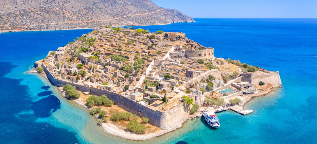 Blick auf die Insel Spinalonga und Boote auf dem Meer.