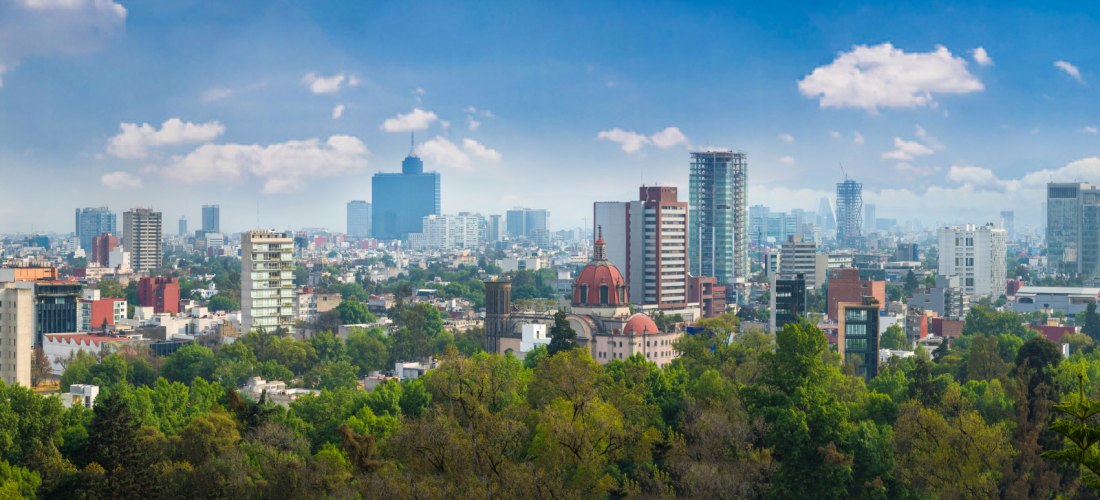 Panoramablick auf eine moderne Stadt mit Hochhäusern, Wohngebäuden und grünen Parks unter einem blauen Himmel mit weißen Wolken