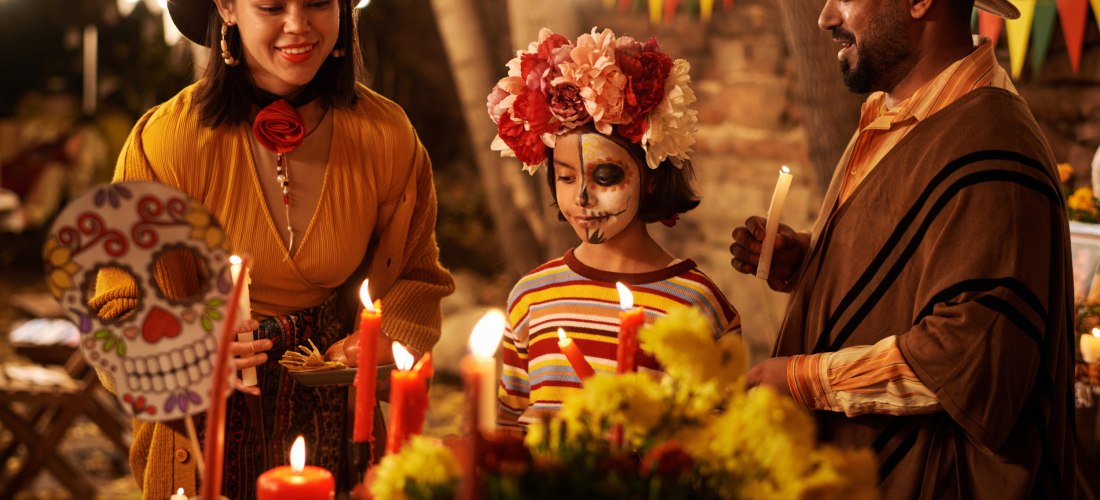 Die Familie feiert gemeinsam den mexikanischen Feiertag, sie steht mit Kerzen am Altar und gedenkt ihrer toten Verwandten