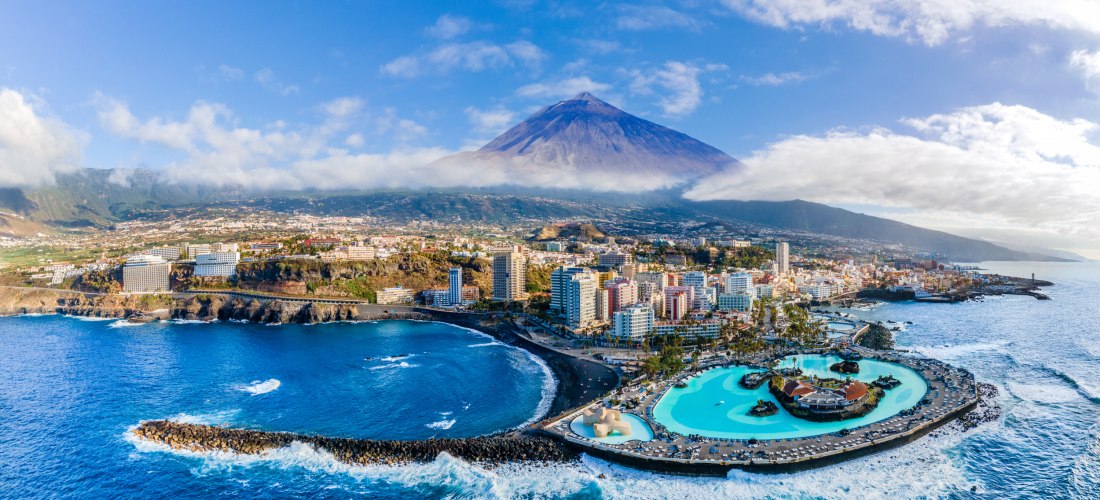 Luftaufnahme von Puerto de la Cruz auf Teneriffa mit Küste, Meerwasser-Schwimmbad Lago Martiánez und dem Teide im Hintergrund