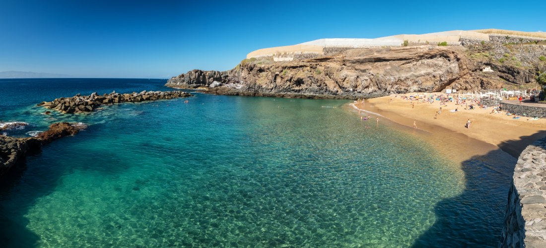 Playa Abama im Südwesten Teneriffas: kleine geschützte Bucht mit goldenem Sand, klarem Wasser und Felsen, Strand des Ritz-Carlton Abama Hotels.