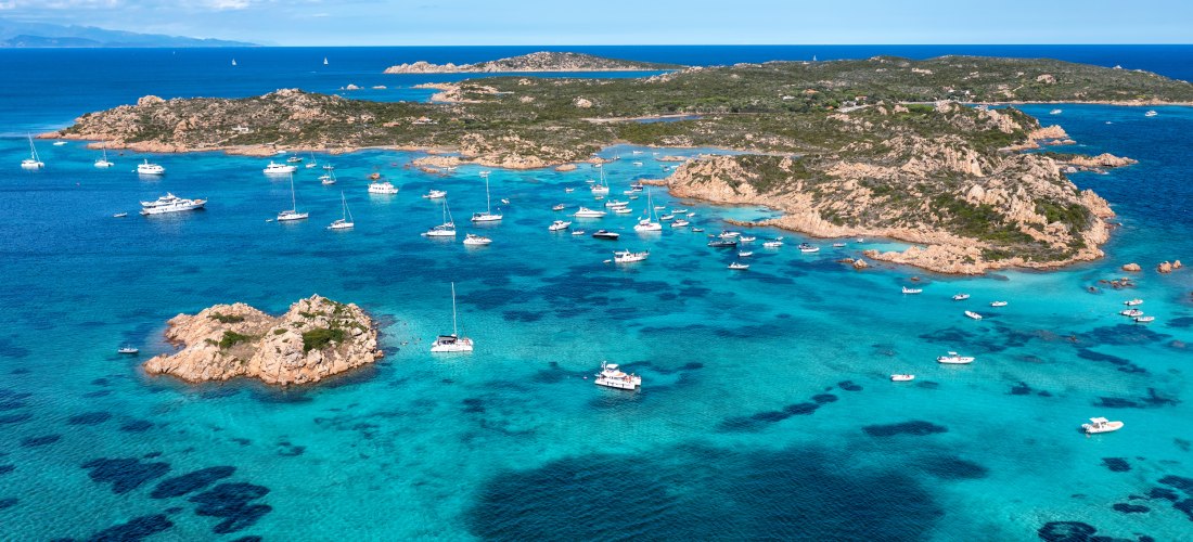 Luftaufnahme des La-Maddalena-Archipels auf Sardinien mit Yachten in türkisfarbenen Buchten und felsiger Küstenlandschaft im Mittelmeer