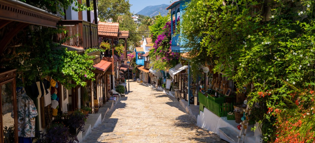 Romantische Altstadtgasse in Kas mit kleinen Geschäften, Balkonen und blühenden Bougainvilleen