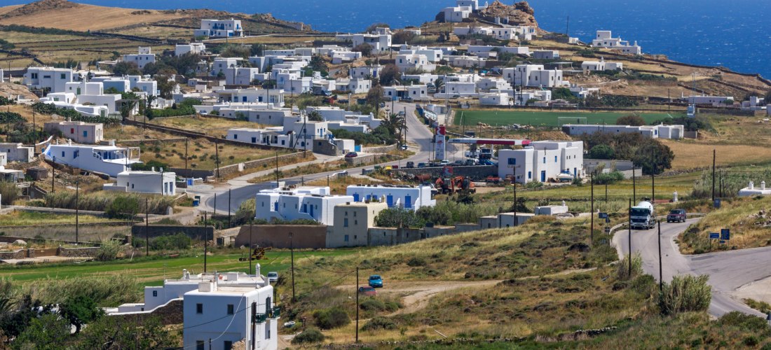 Panoramablick auf das Dorf Ano Mera auf Mykonos mit weißen Häusern und Landschaft bis zum Meer