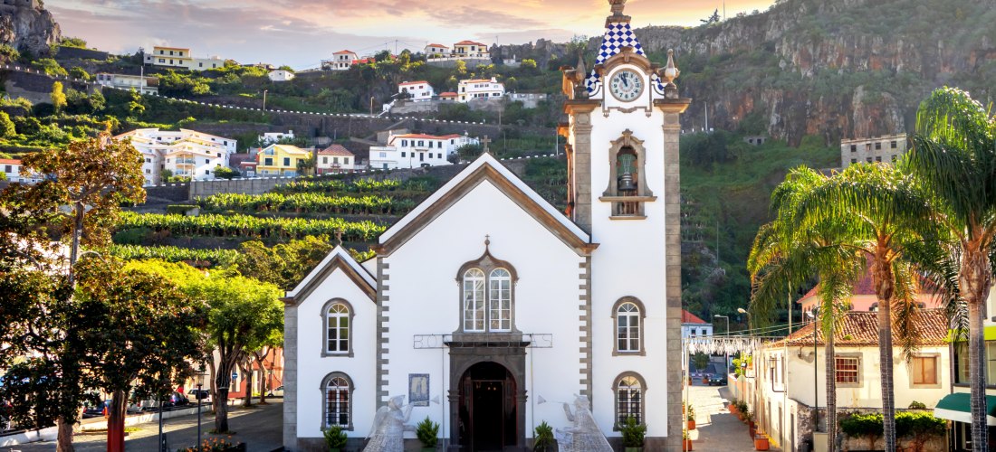Ribeira Brava Madeira – Kirche São Bento im Abendlicht Kirche São Bento in Ribeira Brava auf Madeira mit umliegenden Häusern und Bergen im Sonnenuntergang