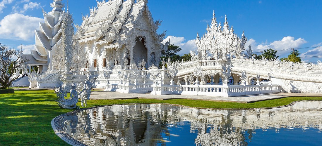 Wat Rong Khun – Der Weiße Tempel in Chiang Rai mit Spiegelung im Teich Der Weiße Tempel Wat Rong Khun in Chiang Rai mit reflektierender Spiegelung im Teich und blauer Himmel