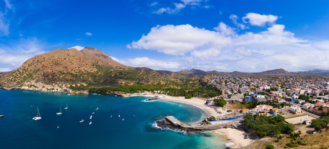 Luftaufnahme von Tarrafal, Santiago – Bucht mit türkisblauem Meer, Sandstrand, Yachten und Stadt am Fuße der Berge auf den Kapverden