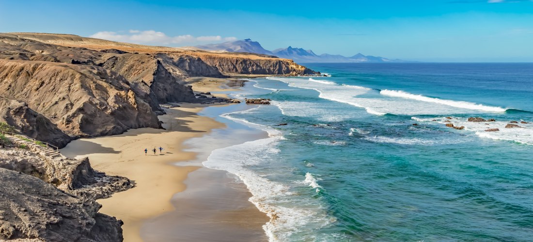 Weitläufiger Sandstrand auf Fuerteventura mit türkisfarbenem Meer
