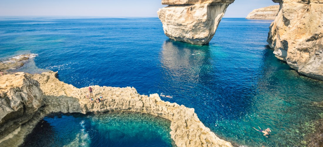 Dwejra Bay auf Gozo mit dem Felsbogen Azure Window und dem beliebten Tauchplatz Blue Hole in der Sonne
