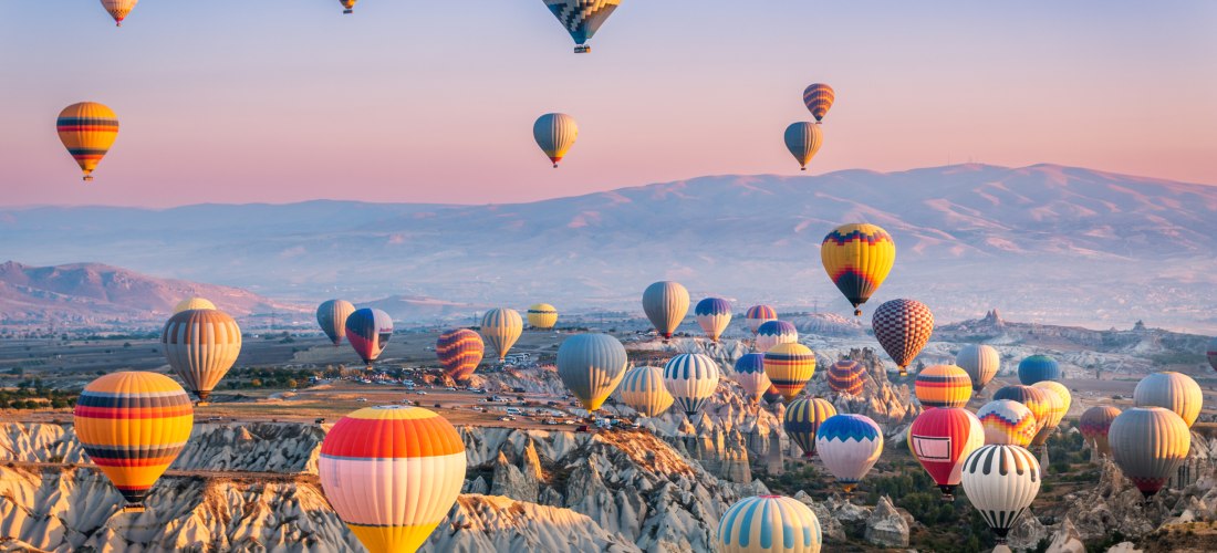Heißluftballons über der bizarren Tuffstein-Landschaft von Kappadokien bei Sonnenaufgang