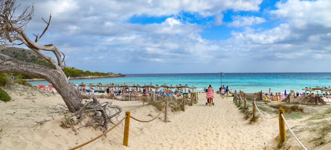 Familien am feinsandigen Strand von Cala Ratjada auf Mallorca mit türkisblauem Meer – ideales Reiseziel für einen entspannten Familienurlaub.