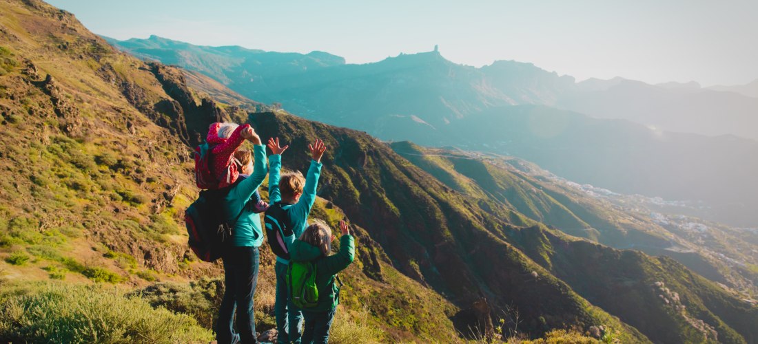 Glückliche Mutter mit Kindern reisen in die Berge bei Sonnenuntergang, Familienwanderung in der Natur